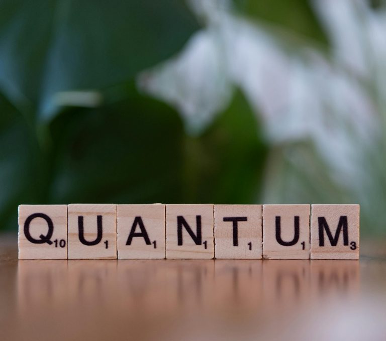 Wooden letter tiles spelling 'Quantum AI' on a blurred background.